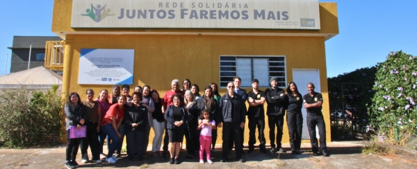 Imagem das pessoas que trabalharam na ação social, com a fachada da ONG ao fundo