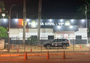 Descrição da Imagem: A imagem mostra uma viatura da Polícia Civil do Distrito Federal (PCDF) estacionada em frente à 10ª Delegacia de Polícia (10ª DP), localizada em Planaltina. A viatura está posicionada de frente para a entrada da delegacia, onde é possível ver parte da fachada, com o nome e o brasão da Polícia Civil.